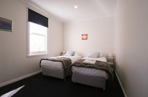 two beds in a small room with a window at Leichhardt Cottages in Relbia