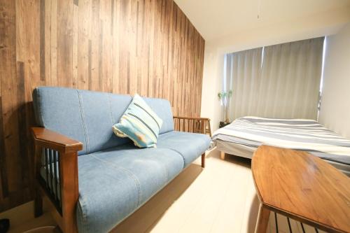 a living room with a blue couch and a bed at Guest House Re-worth Yabacho1 401 in Nagoya