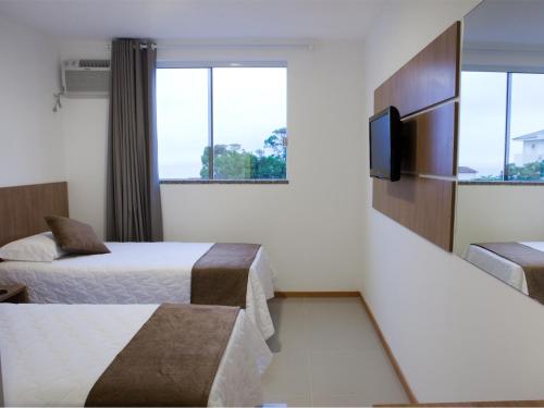 um quarto de hotel com duas camas e uma televisão de ecrã plano em Al Mare Hotel em Florianópolis