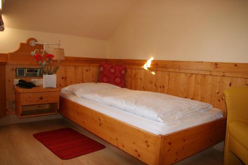 a bed in a room with a wooden wall at Mohnhotel - Bergwirt Schrammel in Zwettl Stadt
