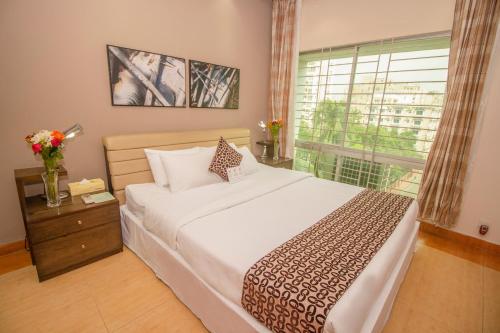 Un dormitorio con una cama grande y una ventana en Rafflesia Serviced Apartments, en Dhaka