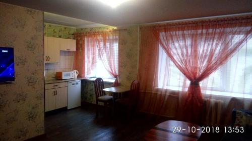 ノリリスクにあるZavenyagina 4 Apartmentの赤いカーテンとテーブル、窓付きのキッチン
