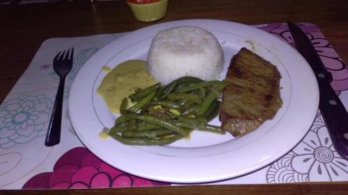a plate of food with meat and green beans and rice at Harena Villa in Morondava