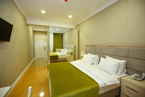 a bedroom with a large bed with a green blanket at Rusel Hotel in Baku