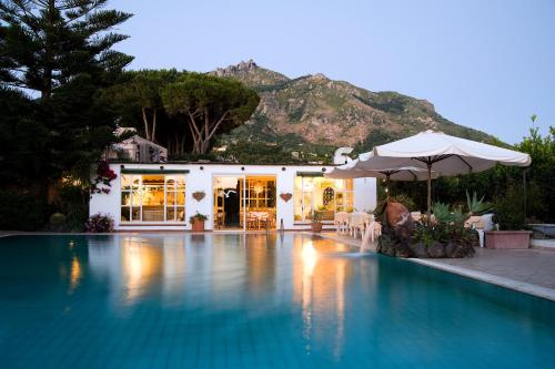 a swimming pool with an umbrella and a house at Hotel Villa Melodie - Adults Only in Ischia