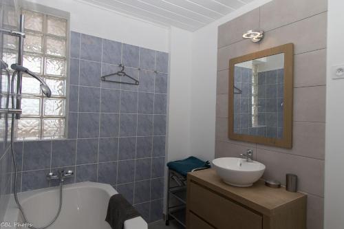 La salle de bains est pourvue d'une baignoire, d'un lavabo et d'un miroir. dans l'établissement L'Eternel Estivant, à Sète