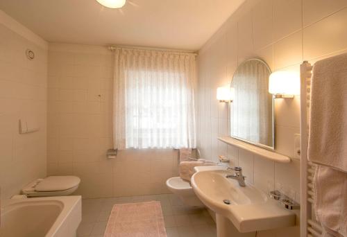 a white bathroom with a sink and a toilet at Gasthof Obermair in Chienes