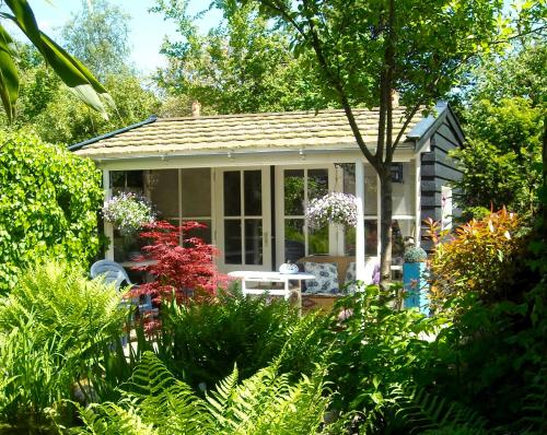 a small house with a table in a garden at Logies Het Tuinhuisje in Enschede