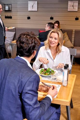 a man and woman sitting at a table eating food at Campanile Saint-Germain-En-Laye in Saint-Germain-en-Laye