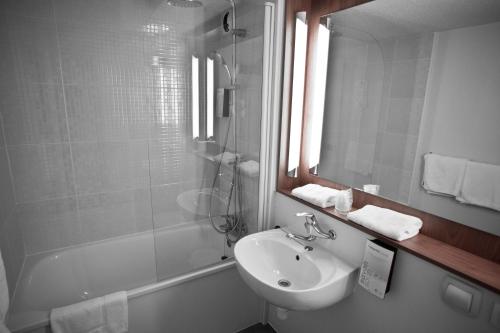 W łazience znajduje się umywalka, lustro i prysznic. w obiekcie Campanile Saint-Germain-En-Laye w mieście Saint-Germain-en-Laye