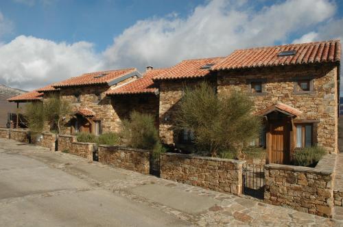 a large stone house with a stone wall at El Bulin de Horcajuelo in Horcajuelo de la Sierra