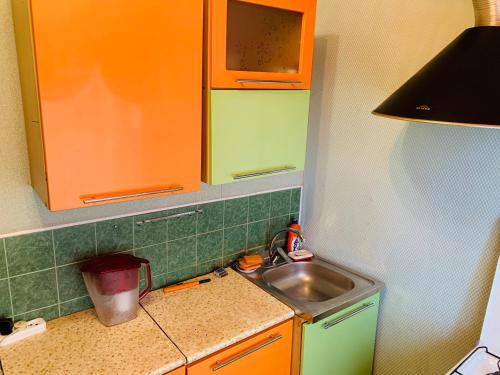 ナディムにあるапартаменты на полярной 14の小さなキッチン(オレンジと緑のキャビネット、シンク付)