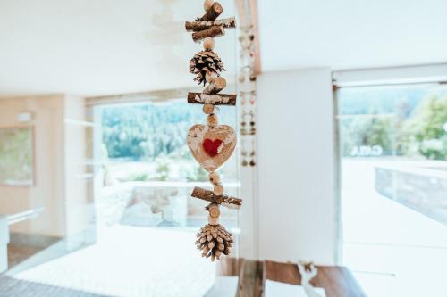 a wooden cross with a heart and pine cones at Gaia Residence Hotel in Mezzana