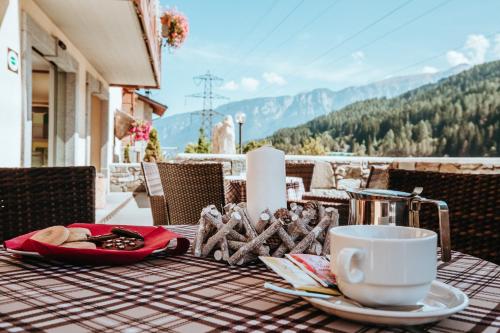 a table with a cup of coffee and a plate of food at Gaia Residence Hotel in Mezzana