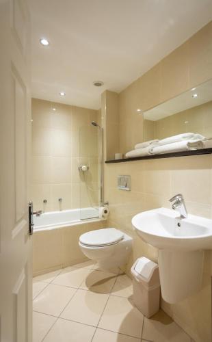 a bathroom with a toilet and a sink and a tub at Kensington Hotel in Llandudno
