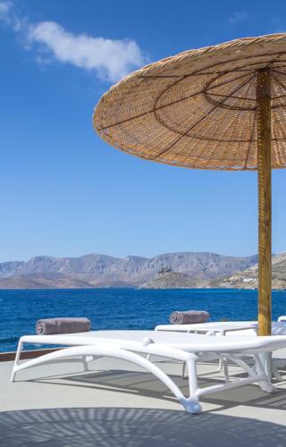 a chair and an umbrella on a deck with the ocean at Carian Hotel in Masouri