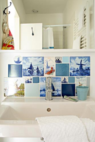 a bathroom with a white sink with pictures on the wall at B&B Noordwijk Binnen in Noordwijk