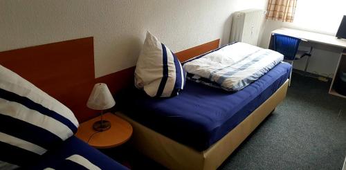 a bedroom with a bed with blue sheets and a desk at Hotel Garni in Herborn