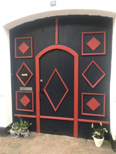 a black garage with a red door and some plants at Ribe Sønderport Bed & Kitchen in Ribe