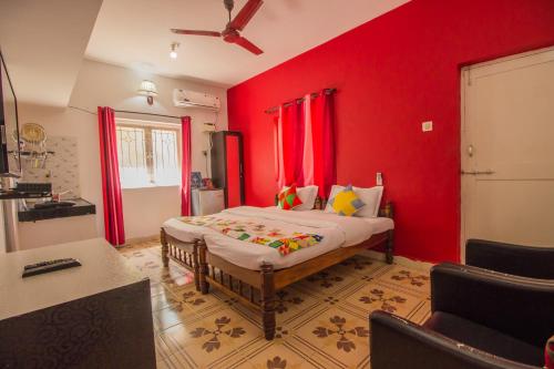 a bedroom with a bed with red walls and a ceiling at Oceanic Pearl Beach Guest House in Calangute