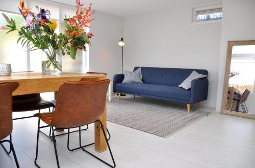 a living room with a table and a blue couch at Beachhouse Bosweg in Noordwijk aan Zee
