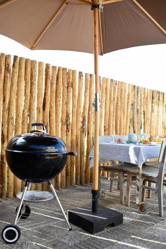 a grill with an umbrella next to a table at Beachhouse Bosweg in Noordwijk aan Zee