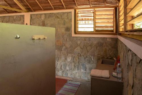 a bathroom with a sink and a stone wall at Les Jardins d'Ankify in Andimaka