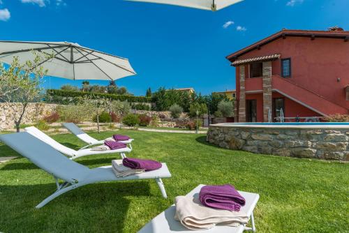 two lounge chairs and an umbrella in a yard at Casale La Desdemona in Sutri