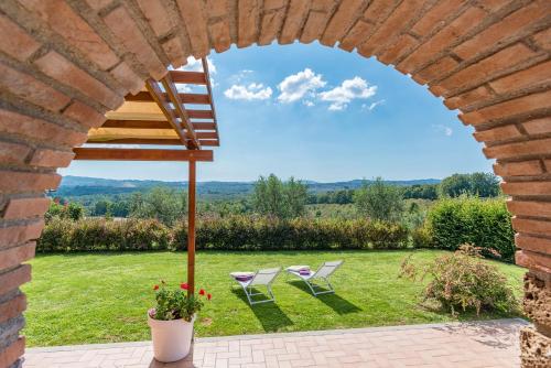 a view through an archway of a yard with two chairs at Casale La Desdemona in Sutri