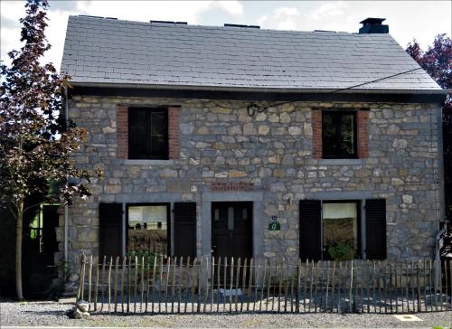 una casa de piedra con una valla delante de ella en Maison d'Engon charme nature, en Beauraing