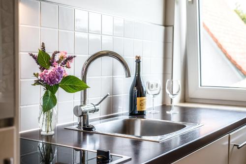 Domizil Familiär في غراتس: حوض المطبخ مع زجاجة من النبيذ والزهور