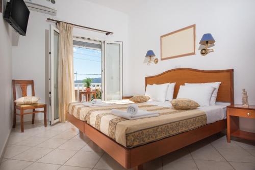 a bedroom with a bed and a window and a television at Hotel Meltemi in Adamantas