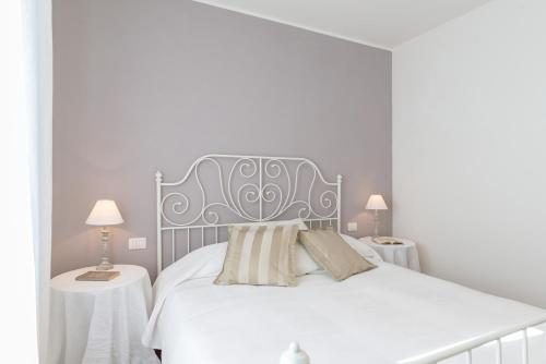 a white bedroom with a large bed with two tables at Casale La Desdemona in Sutri