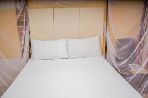a bed with white sheets and pillows on it at Rugems Executive Lodge in Lusaka