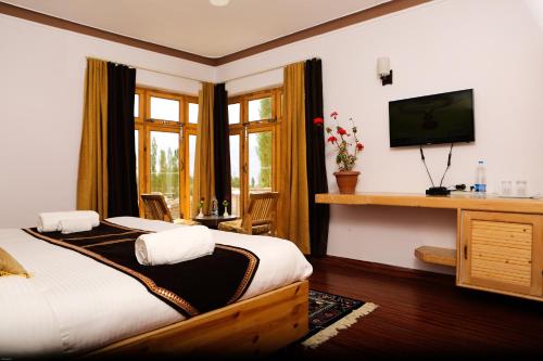 a bedroom with a bed and a desk with a television at HOTEL NATURE's LAND in Leh