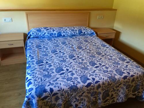 1 cama en un dormitorio con colcha azul y blanca en Hostal-Restaurante Casa Giz, en Cuiña