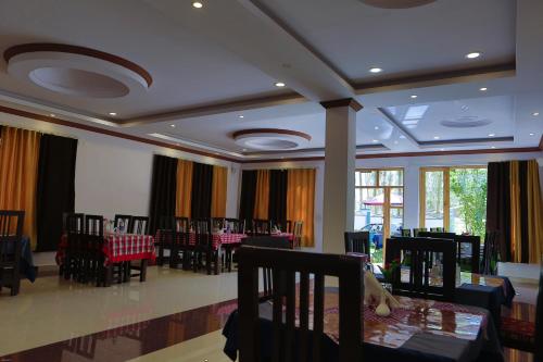 a dining room with tables and chairs and windows at HOTEL NATURE's LAND in Leh