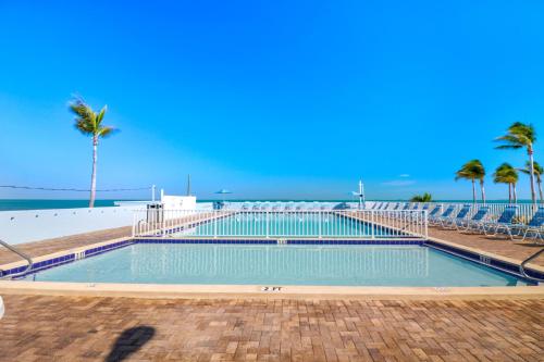 a swimming pool next to a beach with palm trees at Fiesta Key RV Resort Standard ADA Room 5 in Layton