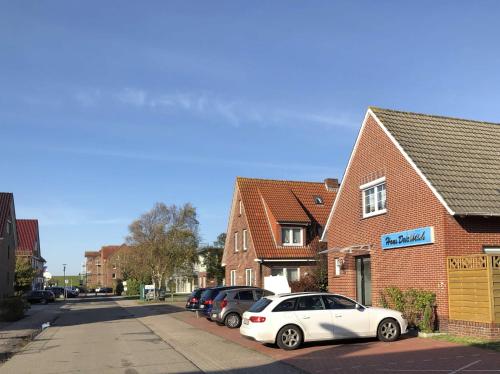 a white car parked in front of a brick building at Pension Deichblick 1 in Norden