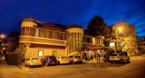 a building with cars parked in a parking lot at Boutique Vila Paradis in Deva