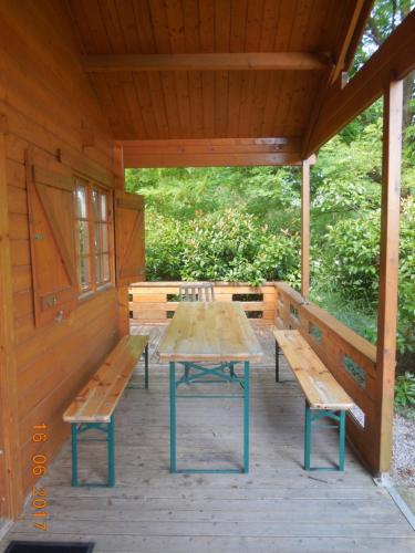 une table de pique-nique et des bancs sur une terrasse en bois dans l'établissement Le chalet bois de Célio, à Coux