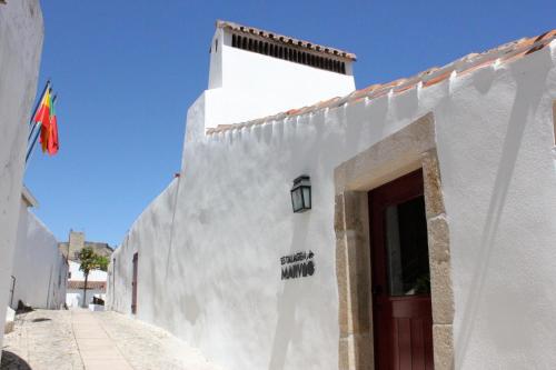 a white building with a red door on a street at Estalagem de Marvão in Marvão