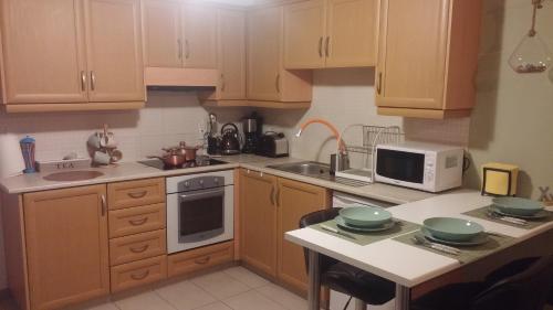 a kitchen with wooden cabinets and a sink and a microwave at Ria Court 33 in Larnaka