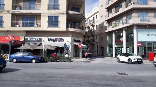 a city street with cars parked in front of buildings at Shore Bridge in Il-Gżira