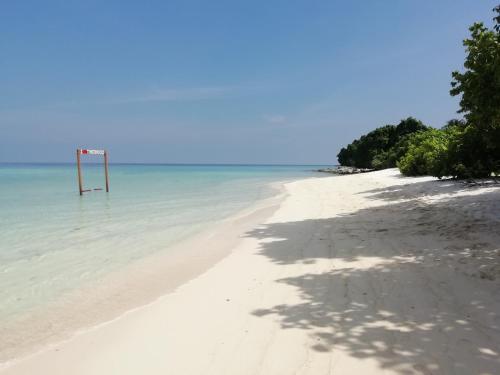an empty beach with a sign in the water at Aqua oasis in Thoddoo