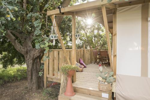 a wooden deck with a swing and a tree at Ciriga Sicily Glamping in Santa Maria Del Focallo