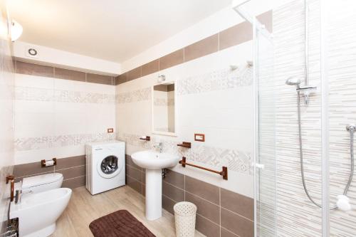 a bathroom with a sink and a washing machine at Villetta Laura 350 mt Baia di Porto Frailis in Àrbatax