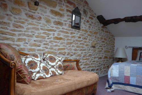 a room with a couch and a stone wall at Le Lavoir de Meziat in Vinzelles