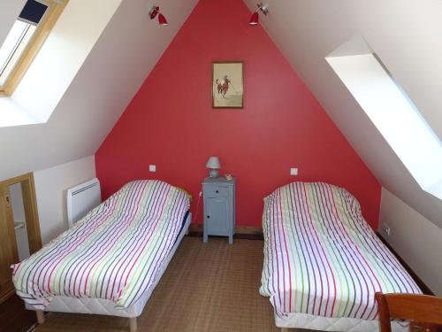 two beds in a room with a red wall at Roch'ar piguet in Carantec