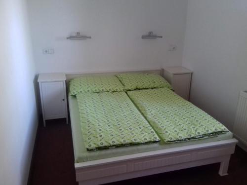 a small bed in a bedroom with green sheets at Hostinec Na Lipce in Havlíčkŭv Brod